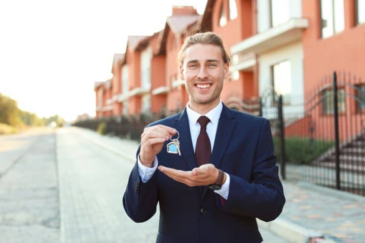 Mortgage Broker Bond - A broker smiling while holding the keys to a house.