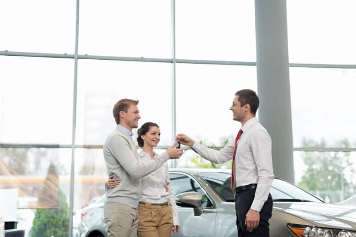 California Motor Vehicle Lessor-Retailer $50,000 Bond - At the dealership, a salesperson is giving the key to its new owner inside the shop room.