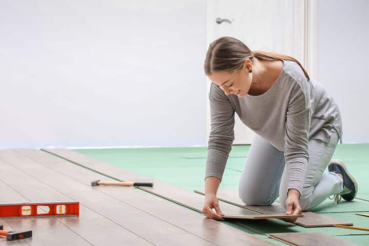 California Lumber Liquidators Inc Installation Provider Bond - Woman installing laminate flooring in her room.