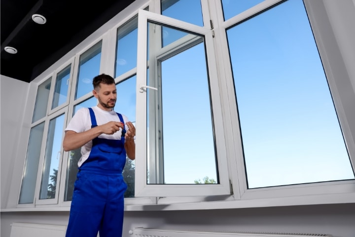 Pasco County, FL - Glass and Glazing Contractor ($5,000) Bond - Construction worker adjusting installed window with screwdriver.