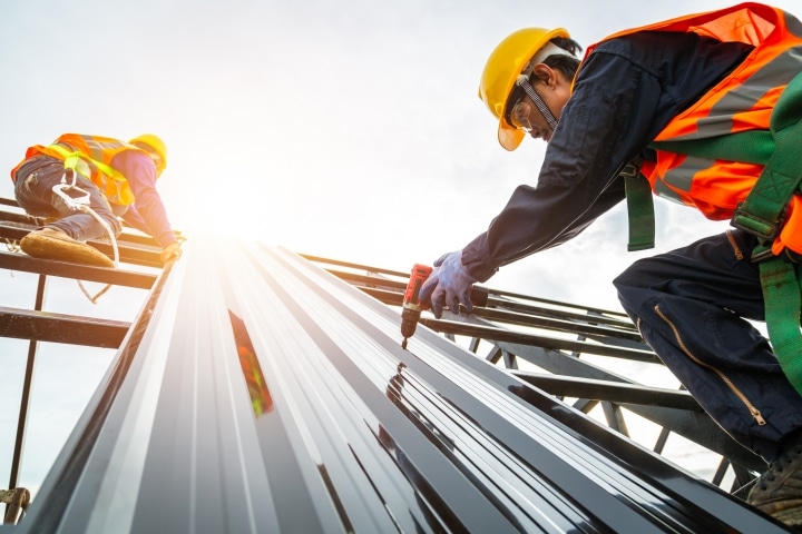 Orange County, FL - Sheet Metal Contractor ($5,000) Bond - Construction worker installing roof metal sheet.