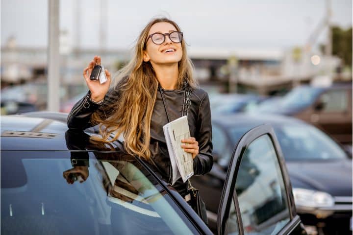 California Auto Information Services ($50,000) Bond - A young woman smiling while holding her key and information document beside her car.
