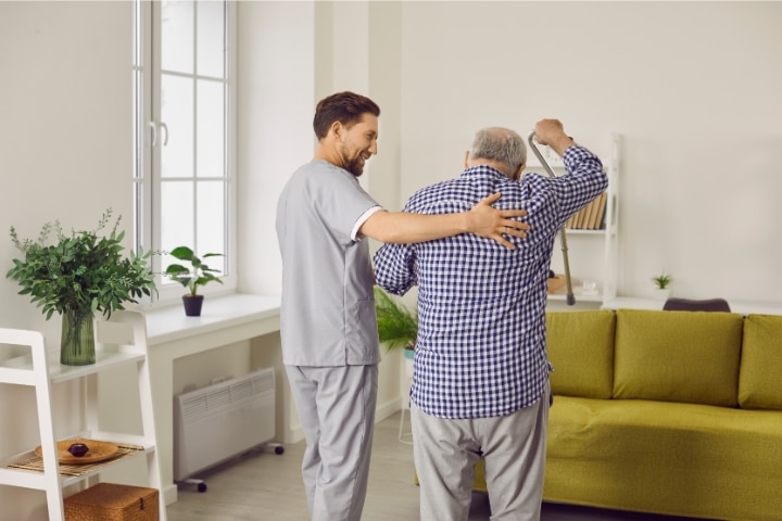 Florida - Assisted Living Facility Bond - Caregiver at an assisted living facility helping a sick, retired senior man.