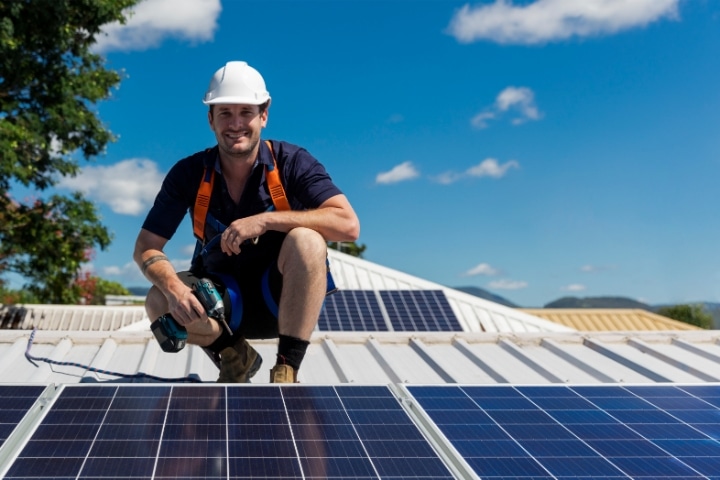Pasco County, FL - Solar Energy Installation Contractor ($5,000) Bond - Solar panel technician with drill installing solar panels at the top of the roof.