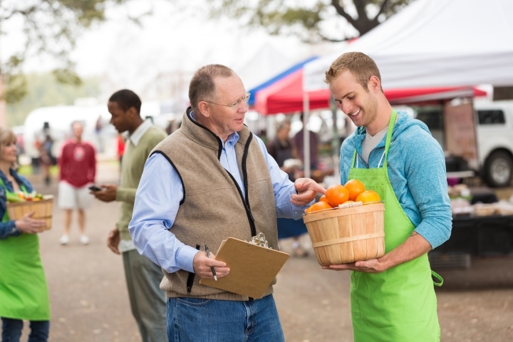 Lee County, FL - Transient Merchant ($5,000) Bond - Senior farmers market manager inspecting produce the vendor.