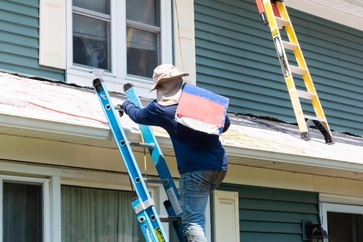 Orange County, FL - Residential Contractor Class C ($5,000) Bond - Contractor climbing ladder carrying package of roof shingles.