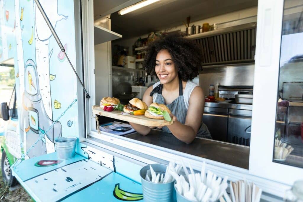 San Bernardino, CA - Temporary Use Permit Bond - Female food vendor offering sandwiches in food van.
