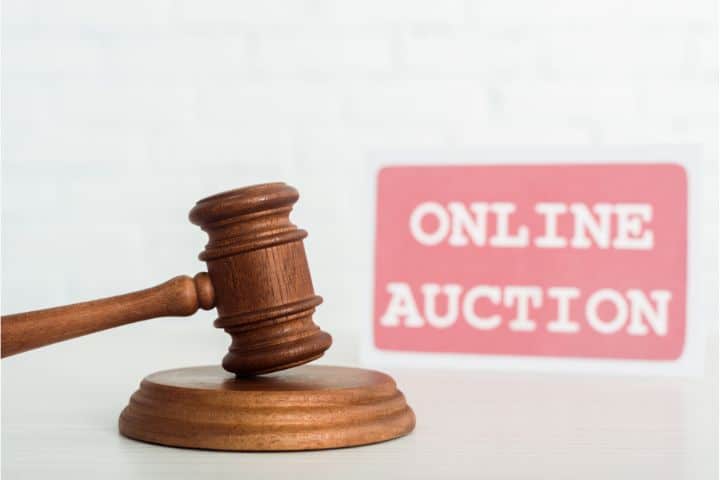 California Auction Company ($20,000) Bond - Selective focus of gavel and card with online auction lettering on background.