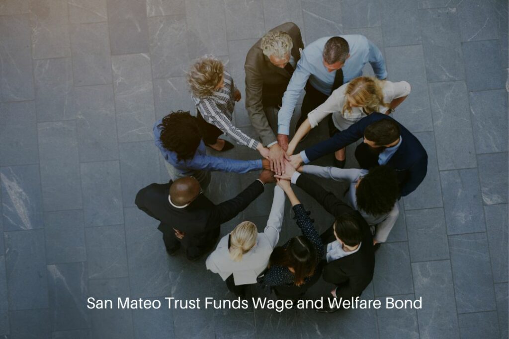 San Mateo Trust Funds Wage and Welfare Bond - Co workers having teambuilding in hall of office standing with hands stacked.