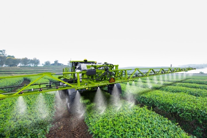 Florida - Fertilizer Dealer ($1,000) Bond - Agricultural tractor spraying fertilizer on green tea fields.