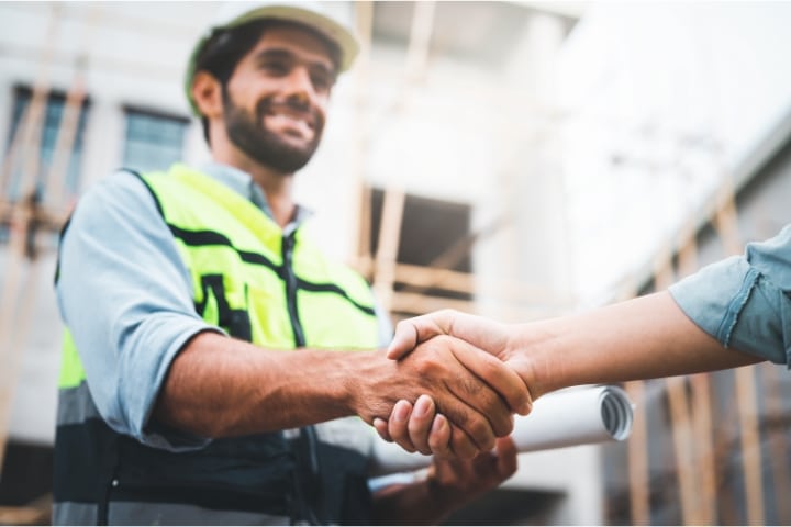 Davenport, FL - License and Permit Bond - Construction worker with his hard hat and blueprint shaking hands.
