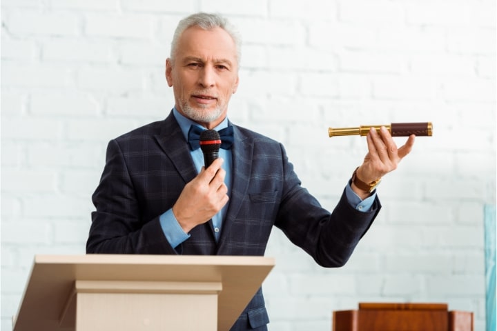 Florida - Auctioneer ($10,000) Bond - Handsome auctioneer in a suit talking with microphone and holding a spyglass during the auction.