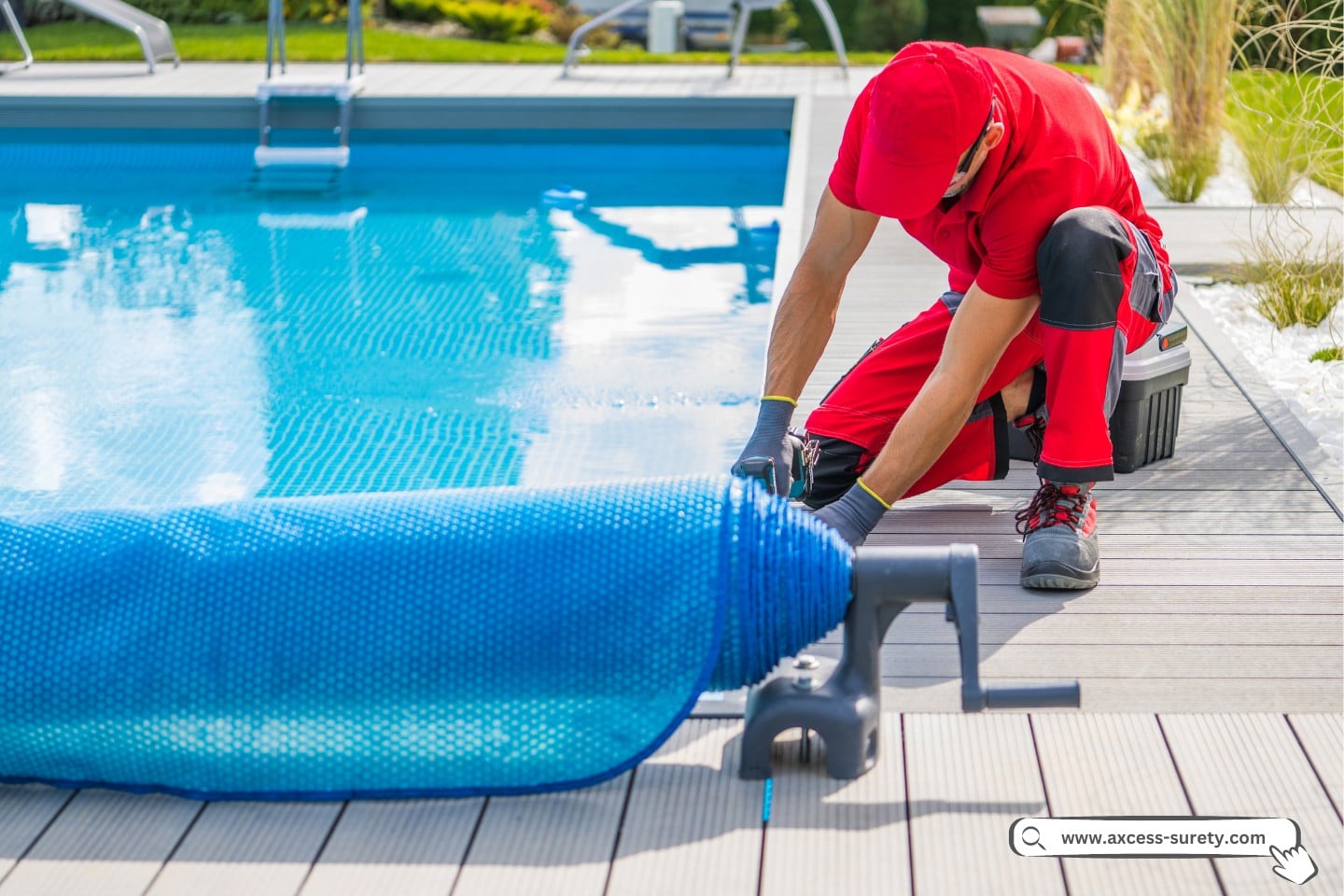 Male technician in red work uniform finishing composite deck installation around residential outdoor swimming pool.