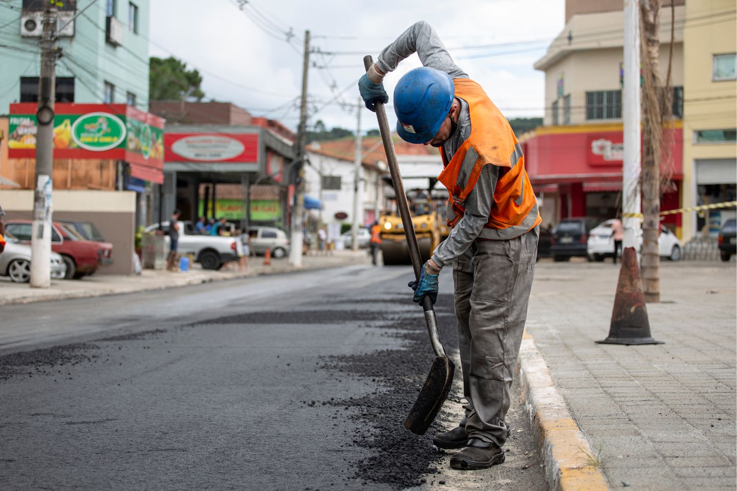 A construction workers applying asphalt in a busy town.