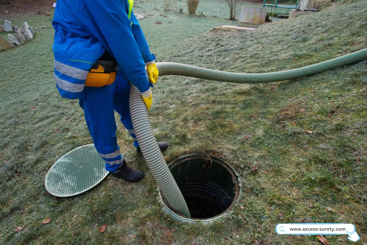 A contractor in blue uniform holding big hose for emptying a household septic tank.