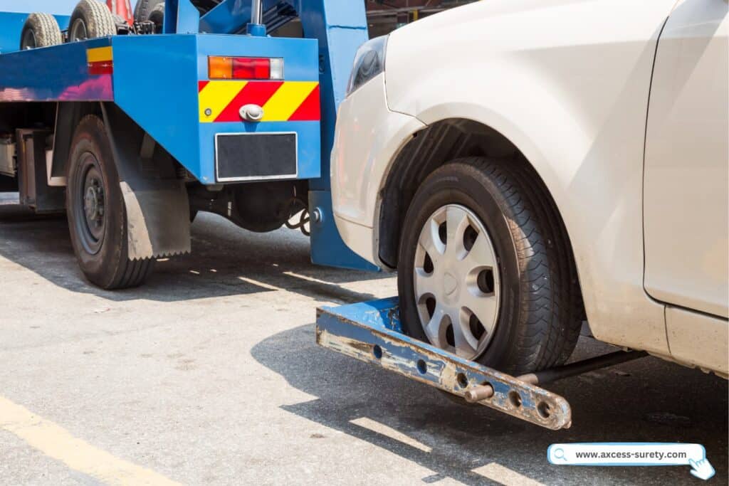 A white automobile being towed on the street by a tow truck.