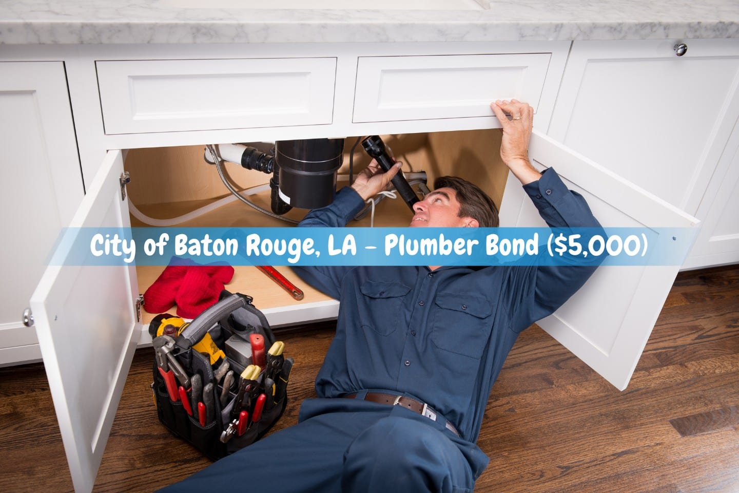City of Baton Rouge, LA - Plumber Bond ($5,000) - A plumber in costume is using his toolbox on the side to fix a kitchen sink.