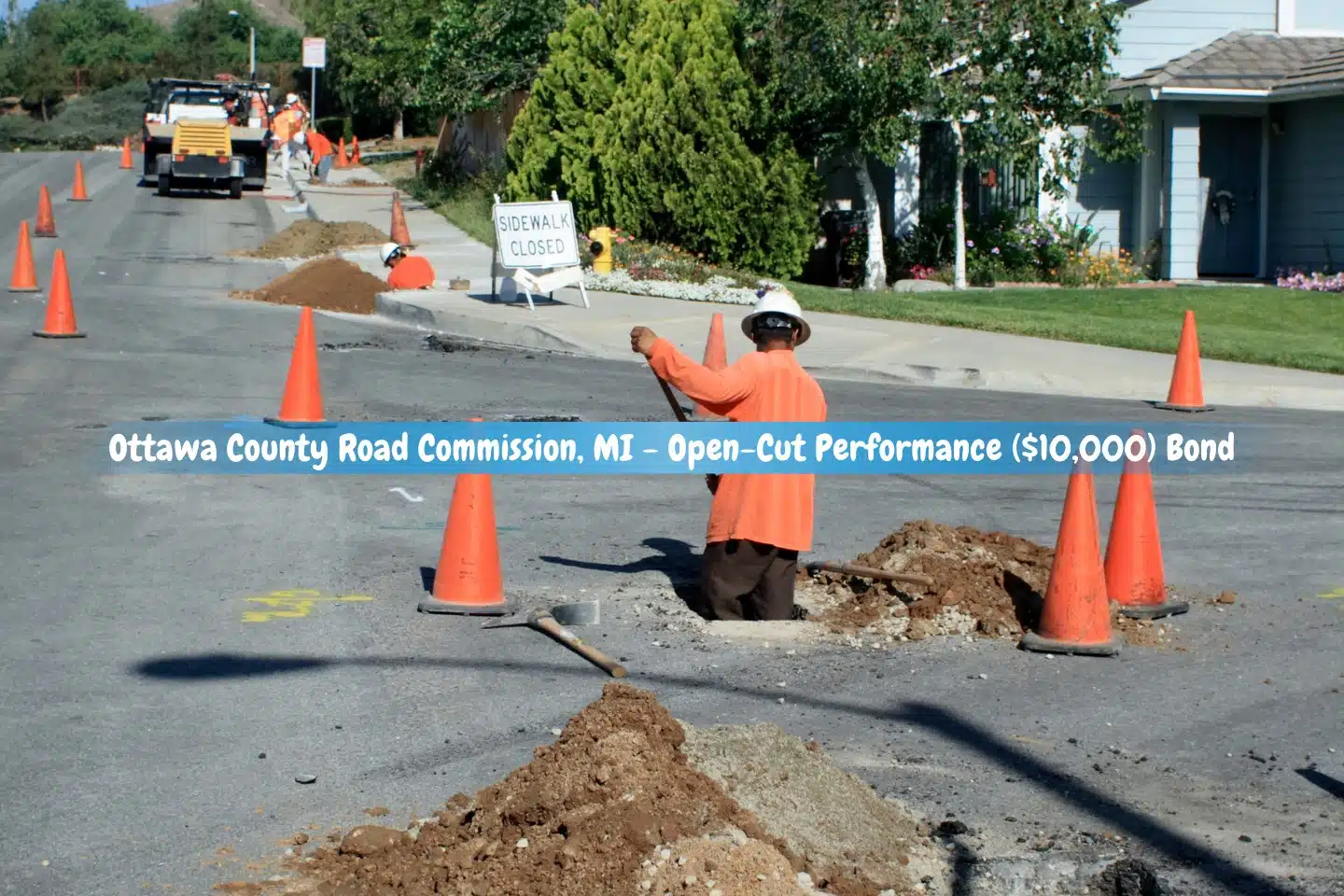 Ottawa County Road Commission, MI - Open-Cut Performance ($10,000) Bond - Construction workers dig up a road to install services in a tract home neighborhood.