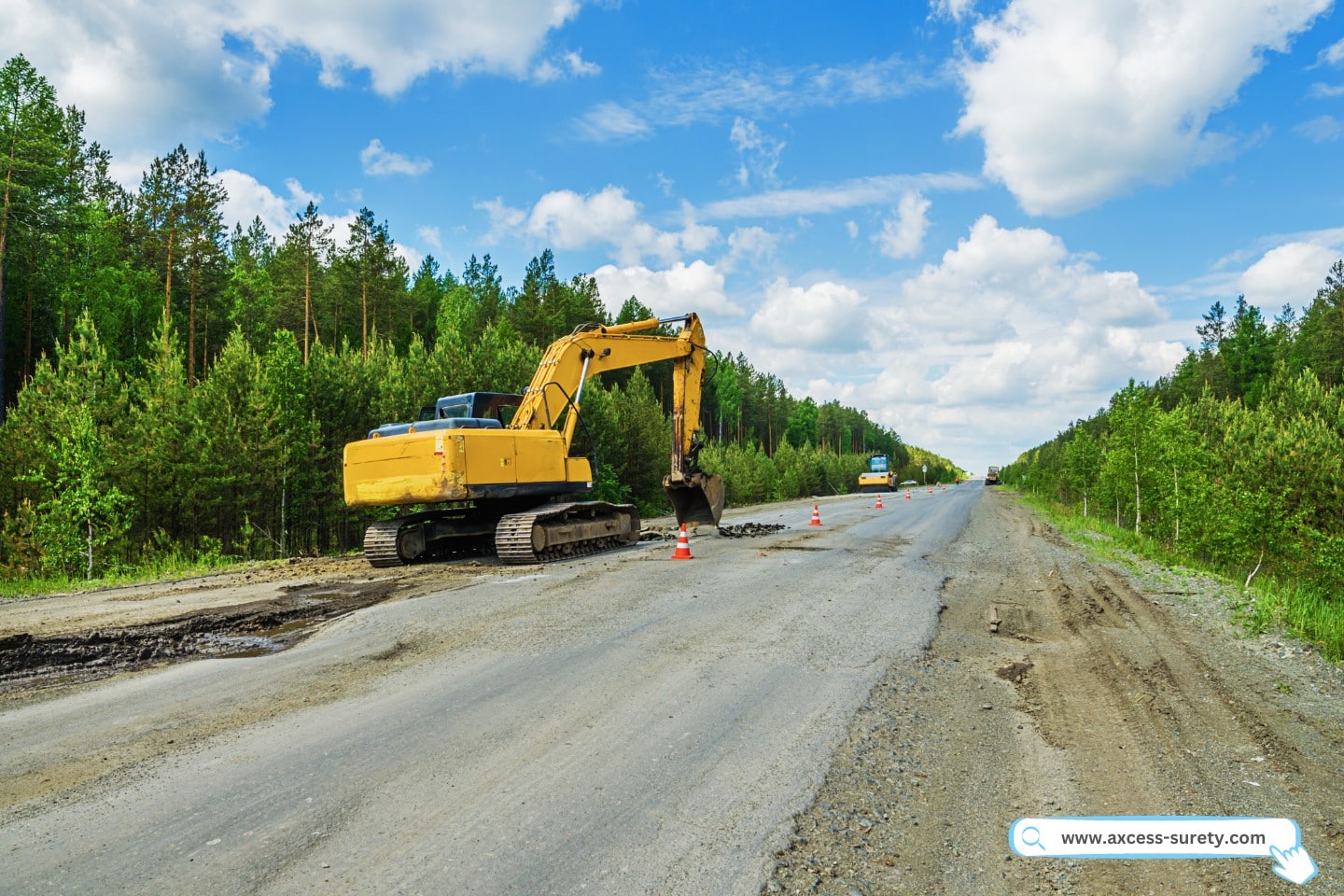 An orange traffic cone serves as a caution while two excavators perform repairs on the highway.