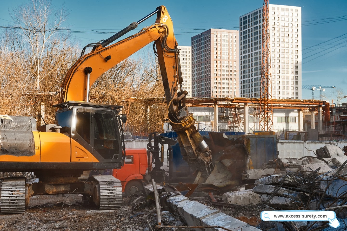 A powerful excavator destroyer collects debris from the demolition site beneath a blue sky.