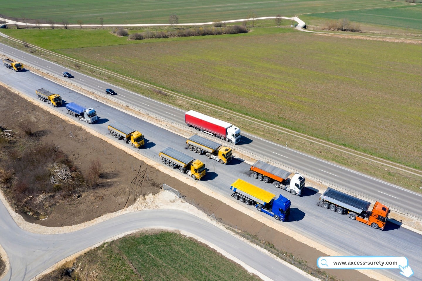 Drivers wait to unload the new and hot asphalt mix onto the prepared asphalt paving equipment.