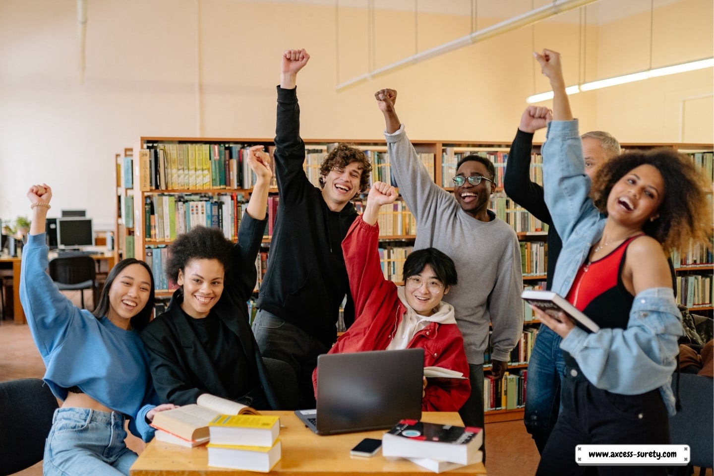 A group of happy pupils standing close to a brown wooden table in the school library.