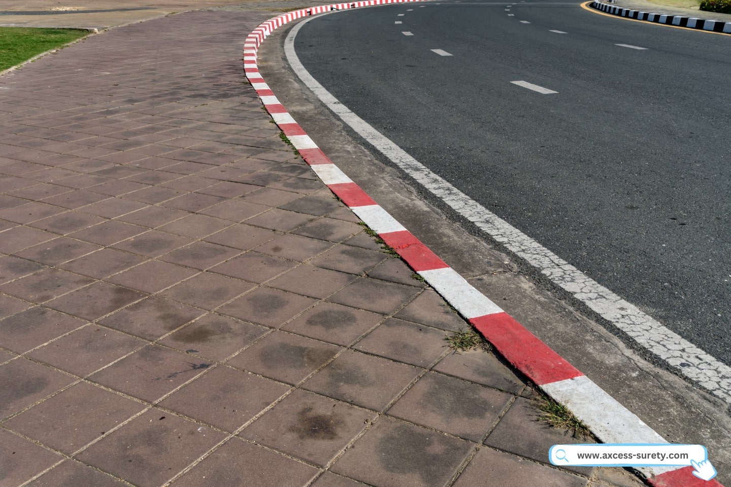 An asphalt road with a red and white concrete curb.