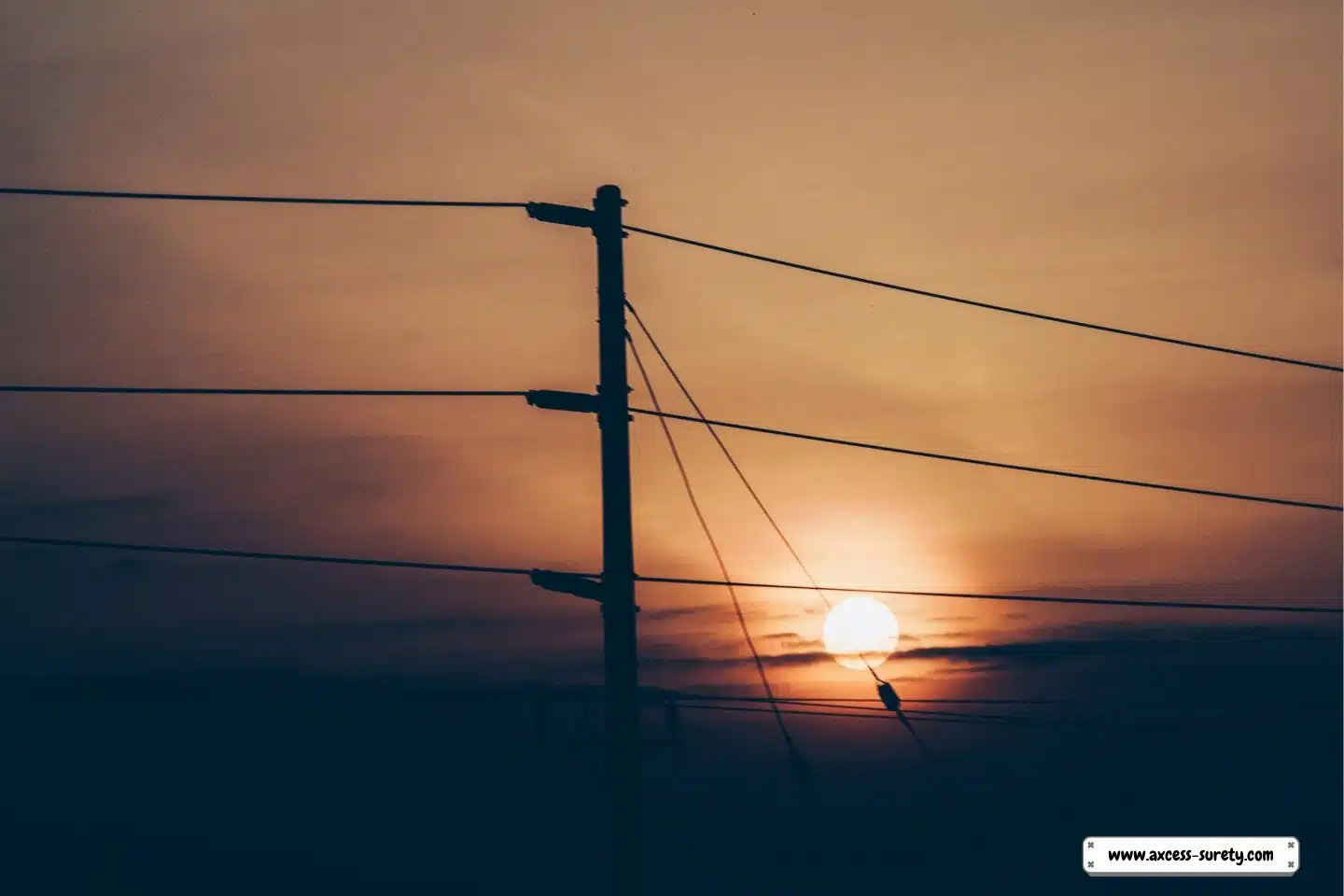 A utility post with power wires in silhouette.