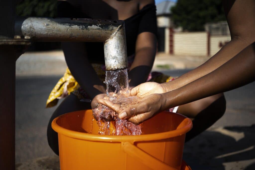 woman pouring water recipient outdoors
