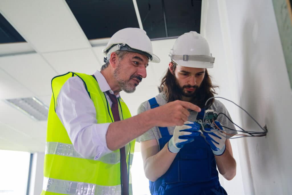 Builder or foreman in working uniform expertising the structure standing with folder at the construction site indoors