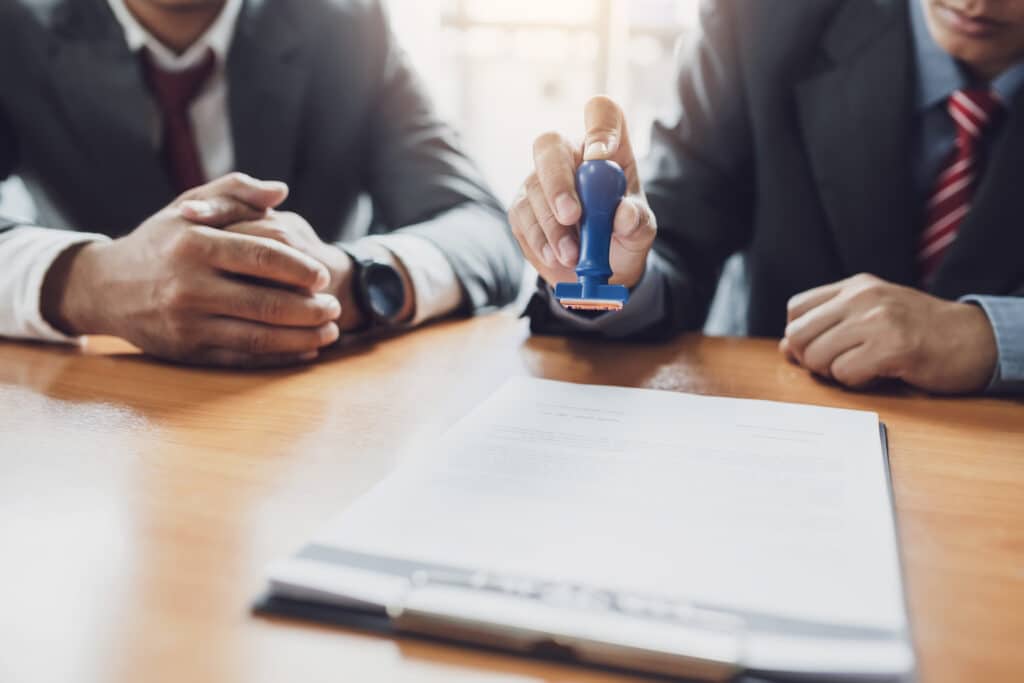 Businessman stamping with approved stamp on document contract.
