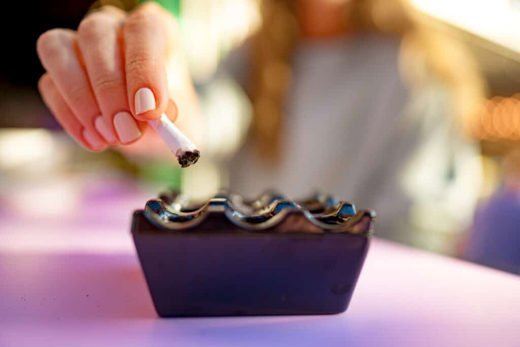 Close up photo of a woman putting finished cigarette in an ashtray