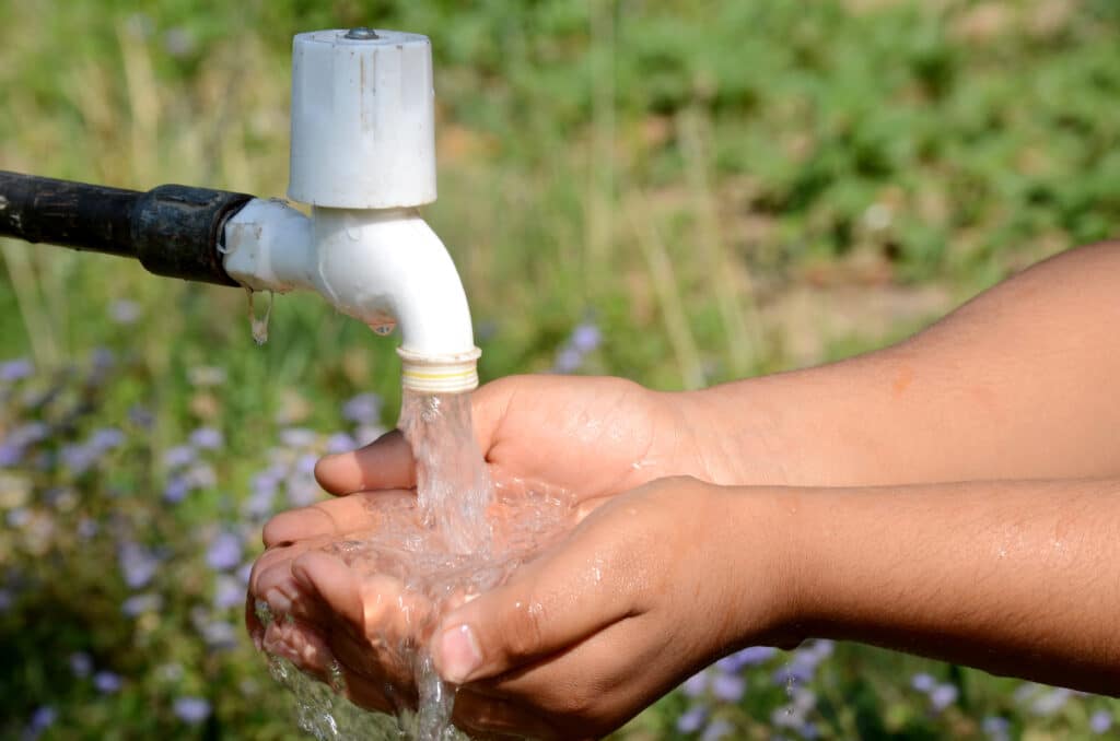 A closeup shot of a person washing their hands with an outdoor tap