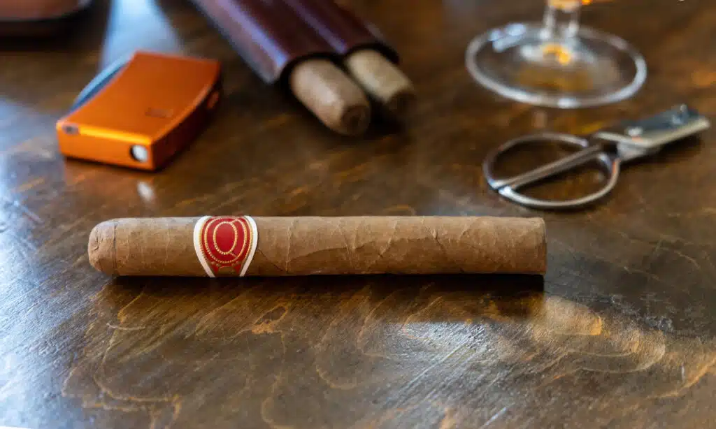Cigar and accessories on a wooden table desk, closeup view. Cuban quality cigar tobacco smoking luxury lifestyle.