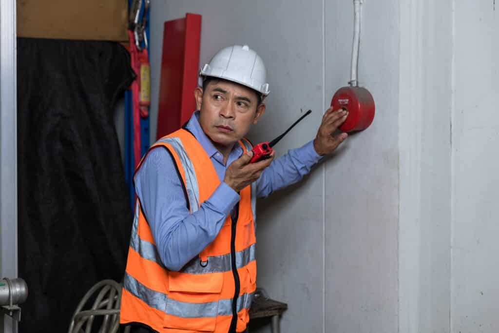 foreman-or-worker-pushing-fire-alarm-on-the-wall-2023-11-27-04-59-16-utc