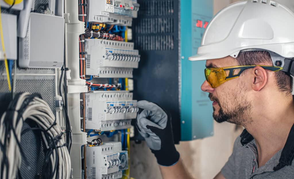 Man, an electrical technician working in a switchboard with fuses. Installation and connection of electrical equipment.