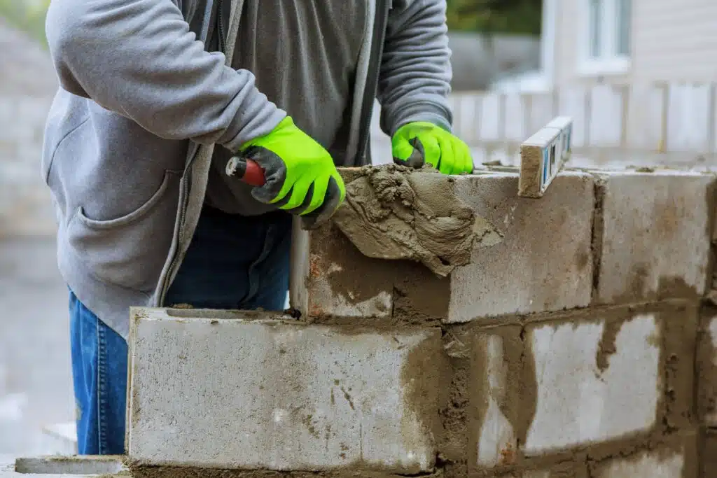 Mason lays down a wall of blocks. wall erection of blocks