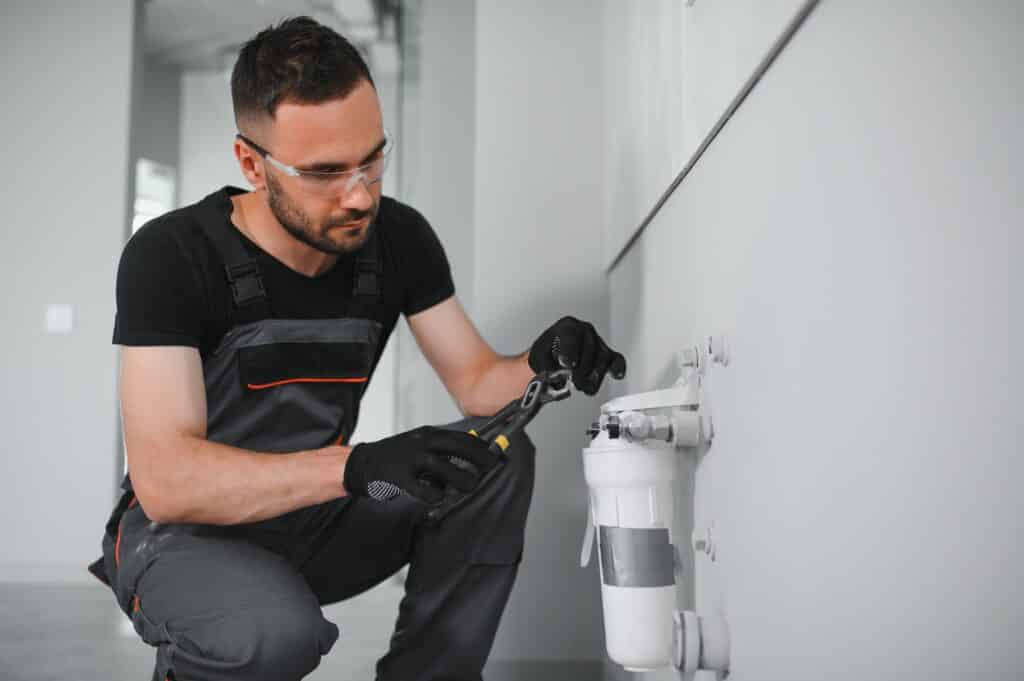 Plumber installs or change water filter. Replacement aqua filter. Repairman installing water filter cartridges in a kitchen. Installation of reverse osmosis water purification system