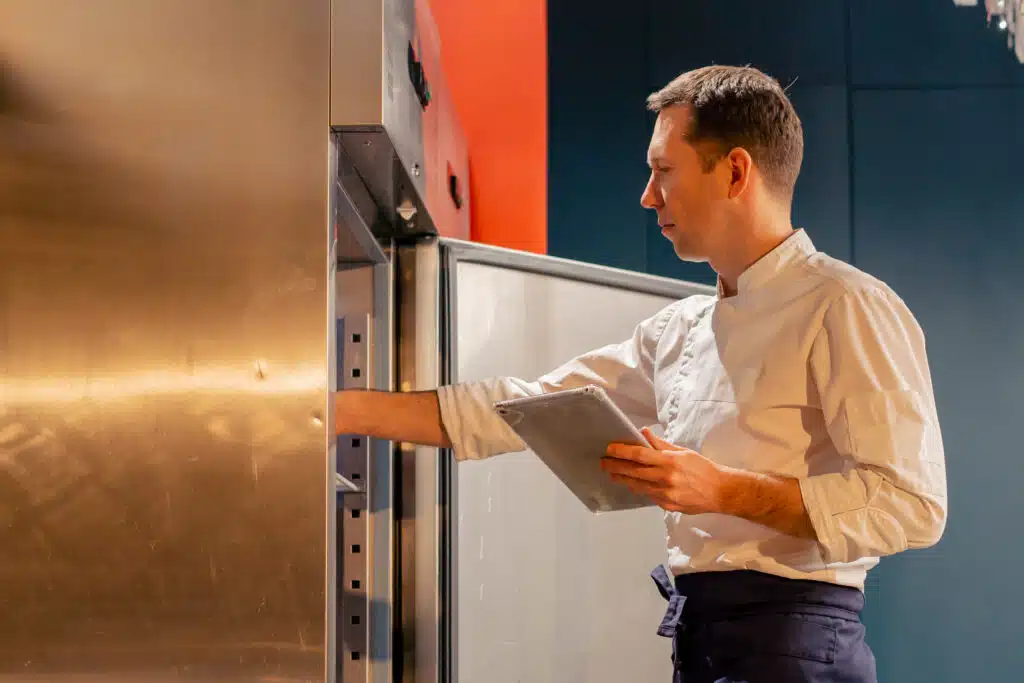 professional kitchen chef looks into fridge and chooses ingredients for cooking food concept