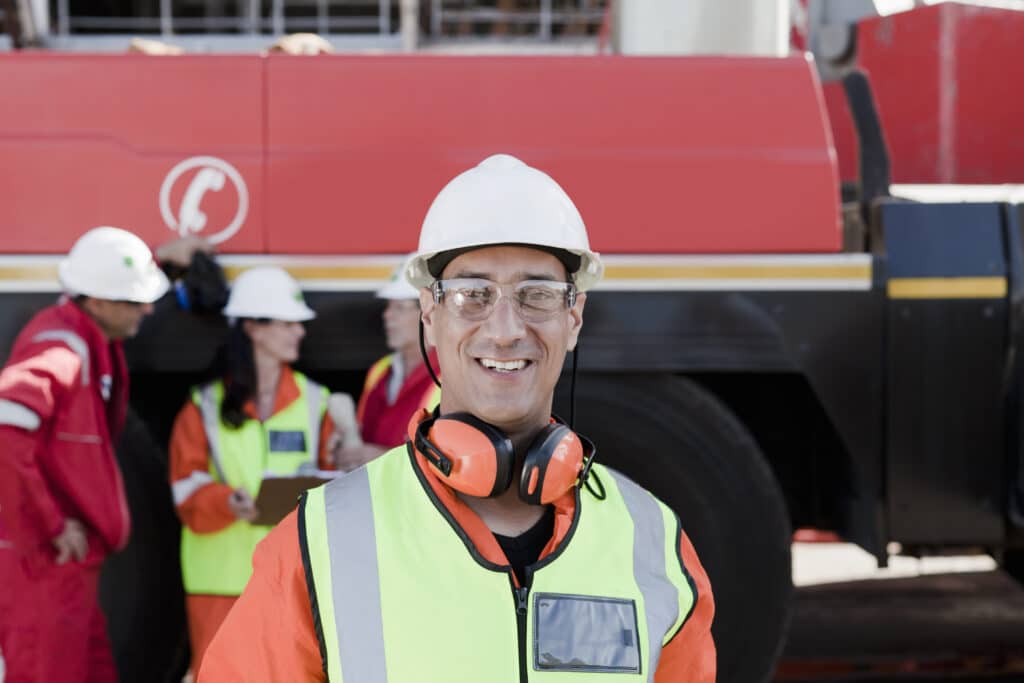 Smiling worker with colleagues at industrial site.