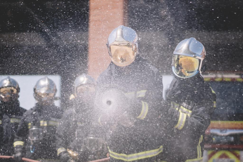 Working firemen throw water with hose.