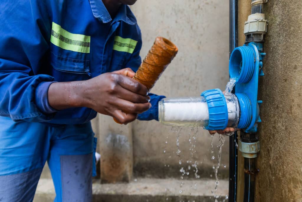 Closeup of African plumber showing one dirty and one clean filters. Changing water filters.