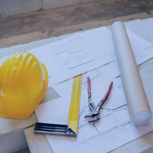 A construction hardhat, tools, and blueprints.