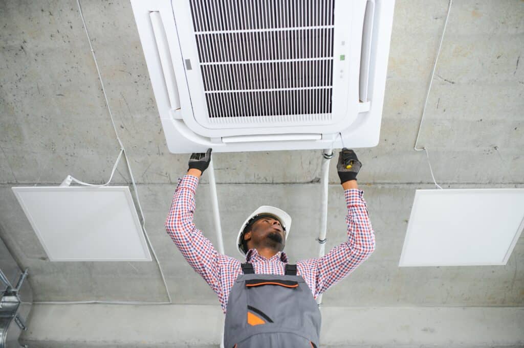 Happy Young African Male Technician Repairing Air Conditioner.
