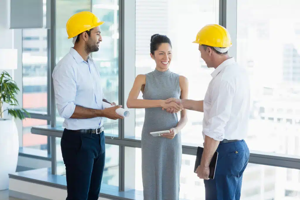 Smiling architects shaking hands with each other in office
