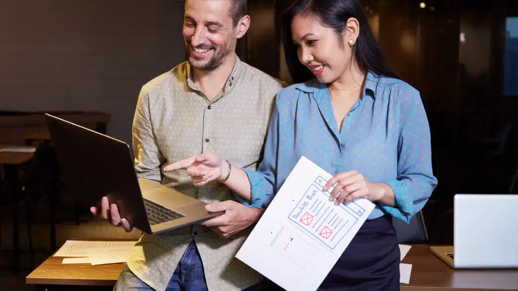 Cheerful developer and UX desinger laughing when looking at laptop screen