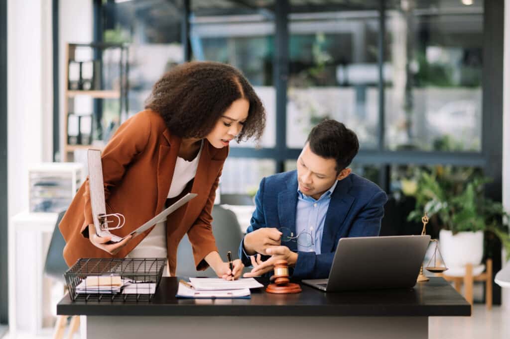 Business and lawyers discussing contract papers with brass scale on desk in office. Law, legal services, advice, justice and law concept .