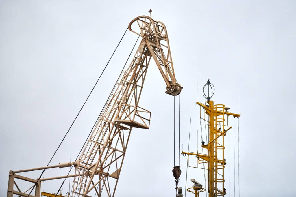 Massive harbor crane in port. Heavy load dockside crane in seaport, cargo container yard, container ship terminal. Business and commerce, logistic. Industrial scene.