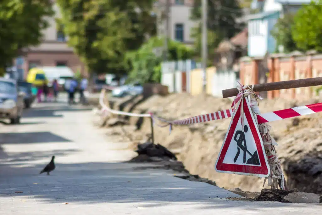 Construction roadwork on street in city. Red safety sign warns about roadworks. Be careful, danger on your way