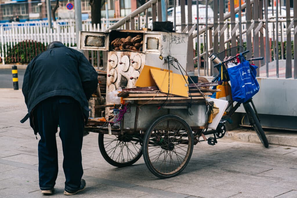 Back view of an older man standing beside his cart in beijing, china